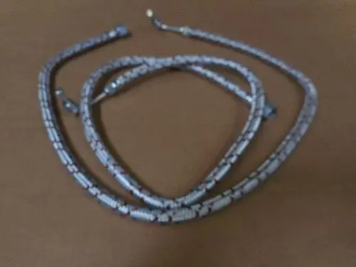Set aus zwei Ölschläuchen mit Remeha-Anschluss, die flexibel und miteinander verknüpft liegen. Der Schlauch hat eine auffällige Musterung und endet in geraden Anschlüssen.